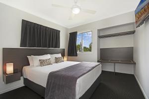 Cooroy Luxury Motel Apartments في Cooroy: غرفة نوم بسرير كبير ونافذة