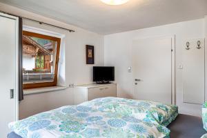 Schlafzimmer mit einem Bett, einem TV und einem Fenster in der Unterkunft Ferienwohnung Galerie Kaiser in Mayrhofen