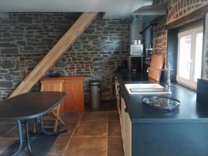 a kitchen with a black counter top and a stone wall at Gîte La Columbia Lens en Hainaut in Cambron-Saint-Vincent