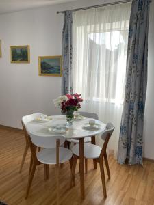 a white table and chairs with a vase of flowers on it at Easy Living Apartments - Old Town in Braşov