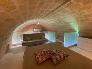 コラートにあるTell me why Pugliaのレンガの壁にソファとベッドが備わる客室です。