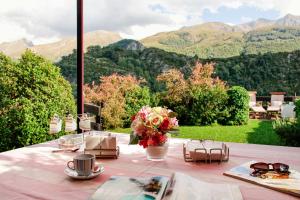 a table with a vase of flowers and a view of mountains at Casa La Hiedra dúplex independiente jardín privado in Panticosa +12 photos