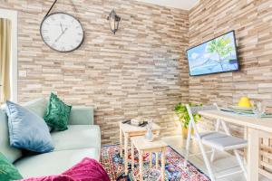 a living room with a couch and a clock on a brick wall at RER C plus parking gratuit à 4 minutes à pieds in Versailles