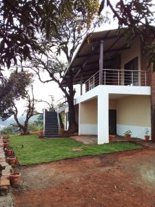 a white house with a tree in front of it at Forest Sunrise Villa 3BHK in Mahabaleshwar