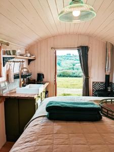 a room with a bed and a sink and a window at Stunning Shepherd's Hut Retreat North Devon in Bideford