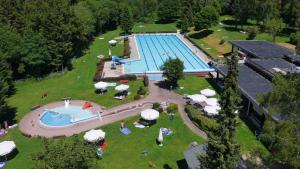 una vista panoramica su una piscina con ombrelloni e persone in un parco di C2 Ferienwohnung im Schwarzwald 30m FerienwohnungApp für max 2 Personen a Menzenschwand