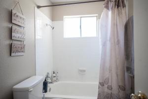 a bathroom with a tub and a toilet and a window at Charming 2 Bedroom House in Las Vegas