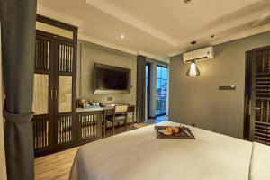 a bedroom with a bed and a desk and a television at Hôtel D’Melin in Vung Tau