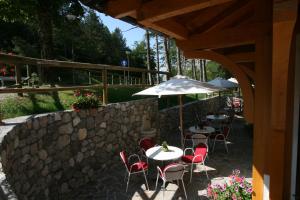 un patio con mesas y sillas y una pared de piedra. en Garni Lago Nembia en San Lorenzo in Banale