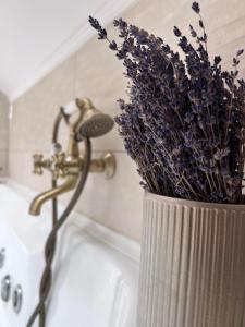 a vase filled with purple flowers sitting on a bath tub at Casa Helen Insurance&Tourism in Gălăuţaş