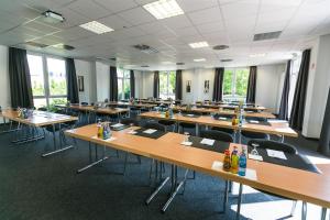 ein leeres Klassenzimmer mit Holztischen und -stühlen in der Unterkunft Hotel Sinsheim in Sinsheim