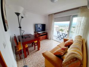 ein Wohnzimmer mit einem Sofa, einem Tisch und einem TV in der Unterkunft APARTAMENTO VISTAS AL MAR, 11 Planta, 50M PLAYA!! in Miramar