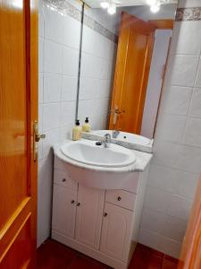 ein Badezimmer mit einem weißen Waschbecken und einem Spiegel in der Unterkunft APARTAMENTO VISTAS AL MAR, 11 Planta, 50M PLAYA!! in Miramar