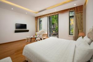 una camera con un grande letto bianco e una TV di Hanoi Kingly Hotel a Hanoi