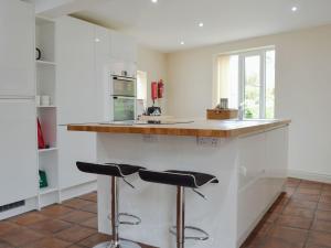 una cocina con 2 taburetes de barra en End Cottage, en Tibthorpe