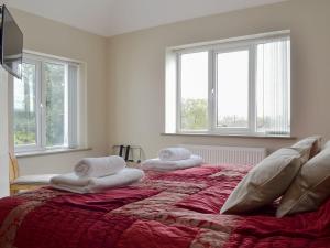 a bedroom with two towels on a bed with windows at End Cottage in Tibthorpe