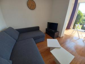 sala de estar con sofá y reloj en la pared en L'Eau-Dyssée, clim, parking privé, jardin, en Saint-Laurent-du-Var