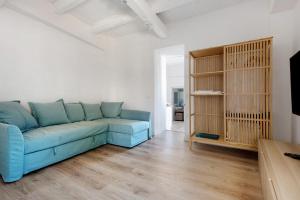 Casa Sol 21 B Garachico في غاراتشيكو: غرفة معيشة مع أريكة زرقاء وأرضيات خشبية