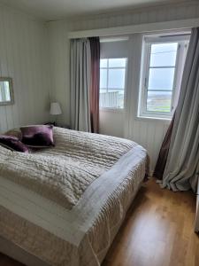 a bedroom with a large bed and two windows at Villa Myklebostad in Breidvika