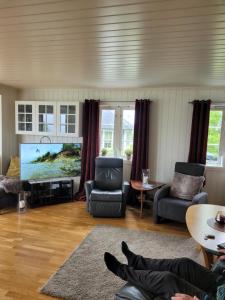 a living room with a flat screen tv and furniture at Villa Myklebostad in Breidvika