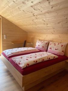 Cama en habitación de madera con almohadas en Appartements Zint, en Sankt Gallenkirch