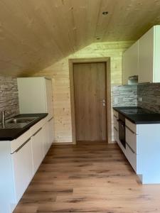een keuken met witte werkbladen en een houten vloer bij Appartements Zint in Sankt Gallenkirch