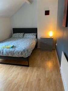 a bedroom with a bed and a lamp on a wooden floor at The Superhost - 4 BR House in Sunderland