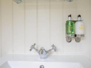 a bathroom sink with a faucet and two bottles on the wall at Under Willows - Uk12608 in Burton Overy