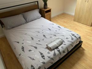 Una cama en un dormitorio con una colcha con plumas. en The Vacationers - Pvt Rooms with Shared Bath en Sunderland