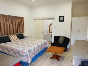 a small bedroom with a bed and a chair at Danodeb Lodge in Pietermaritzburg