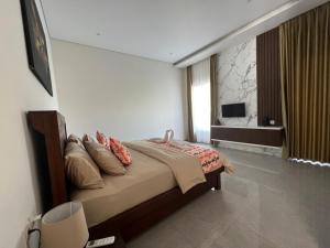 um quarto com uma cama com almofadas e uma televisão em Villa Niang Ando em Labuan Bajo