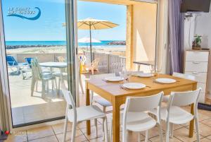 a dining room with a table and chairs and a balcony at Le chant des vagues in Frontignan