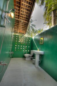 een groene badkamer met 2 toiletten en een wastafel bij The Green Rooms Surf & Yoga Camp - ON THE BEACH - Prime location Weligama Bay in Weligama