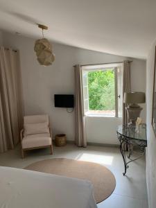 - un salon blanc avec une fenêtre et une chaise dans l'établissement Mas Saint Antoine, à Grasse