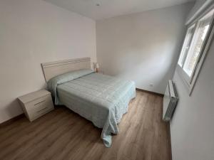 1 dormitorio con 1 cama y suelo de madera en Apartamento vacacional en Redondela