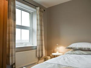 een slaapkamer met een bed en een raam bij Slaters Cottage in Middleham