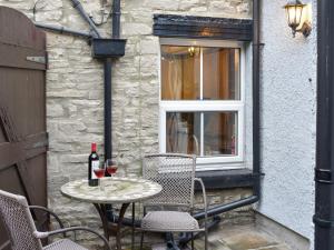 a table with two chairs and a bottle of wine at Slaters Cottage in Middleham