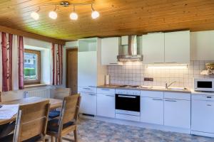 a kitchen with white cabinets and a wooden ceiling at Ferienwohnung Oberangerhof in Kaltenbach