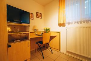 Zimmer mit einem Schreibtisch, einem TV und einem Stuhl in der Unterkunft Hotel Abenstal in Au in der Hallertau