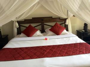 um quarto com uma cama grande e almofadas vermelhas e brancas em Bali Villa Djodji em Ubud