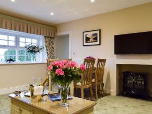 een woonkamer met een vaas met bloemen op een tafel bij The Lodge Cottage in Keilour