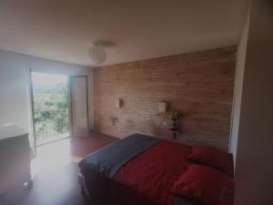 sypialnia z drewnianą ścianą z łóżkiem i oknem w obiekcie Les chambres de Sophie w mieście Chalabre