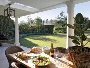 a table with a bowl of salad and a bottle of wine at Woodlands Villa in George