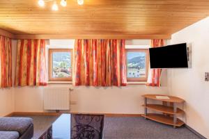 a living room with a tv and two windows at Ferienwohnung Oberangerhof in Kaltenbach