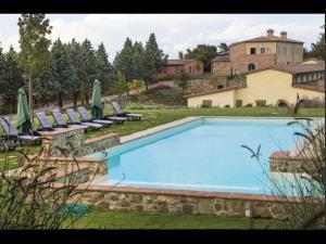Appartament Rosmarino - Cignella Resort في Osteria Delle Noci: مسبح كبير مع كراسي ومنزل