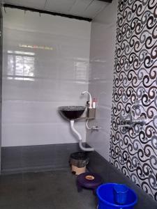 a bathroom with a sink on a white wall at Bageecha B&B- Vaayu in Alibaug