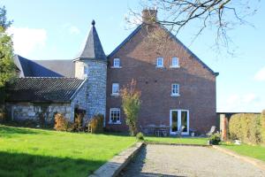 un gran edificio de ladrillo con una aguja en un campo en Gite des Comagnes, en Limbourg