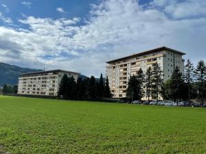 dos edificios en un campo con un campo verde en Seeappartement LUNA am Ossiachersee, en Bodensdorf