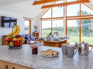 a kitchen with a table with a bowl of fruit on a counter at Sunnyside House in Duthil