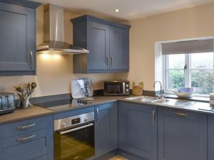 a kitchen with blue cabinets and a sink at Olivia - Uk13137 in Barnby Moor